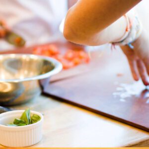 Basil in a small white bowl near a cutting board
